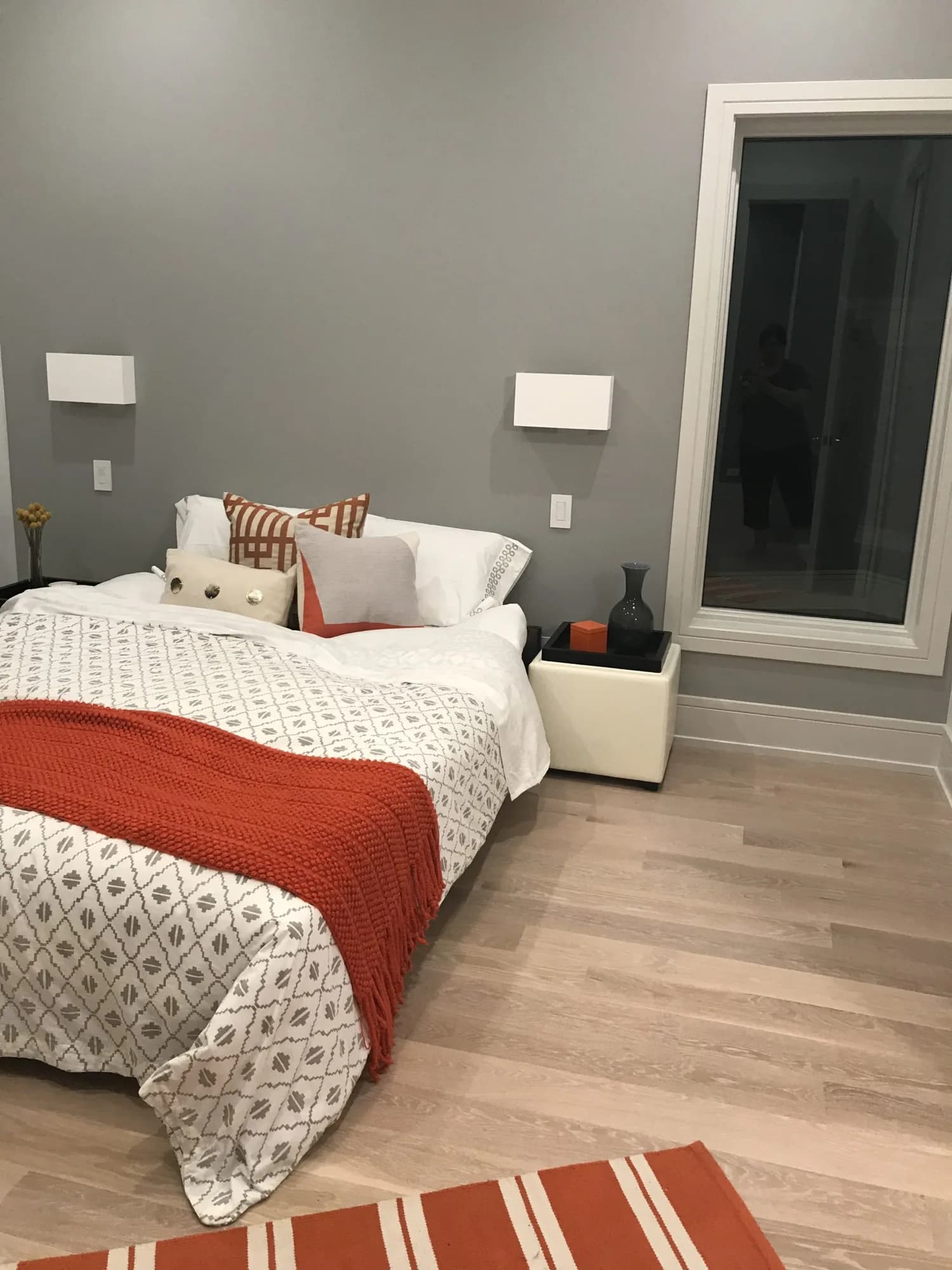 Pale wood flooring in a bedroom with gray walls and a red throw.