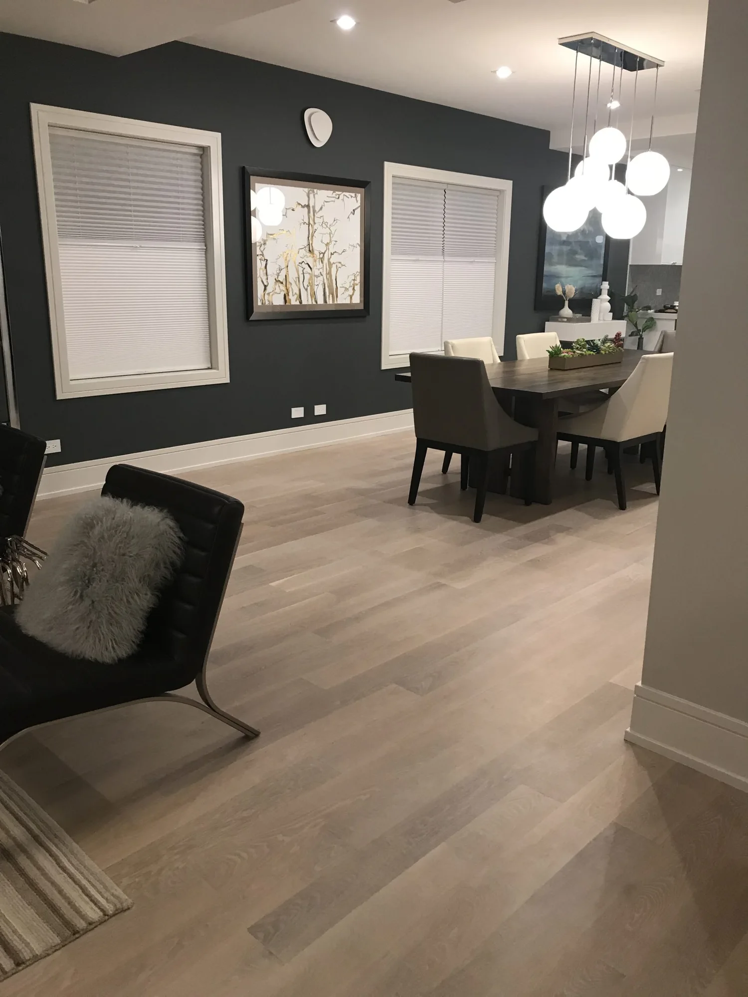 Pale wood floor leading from a sitting area into a dining room.