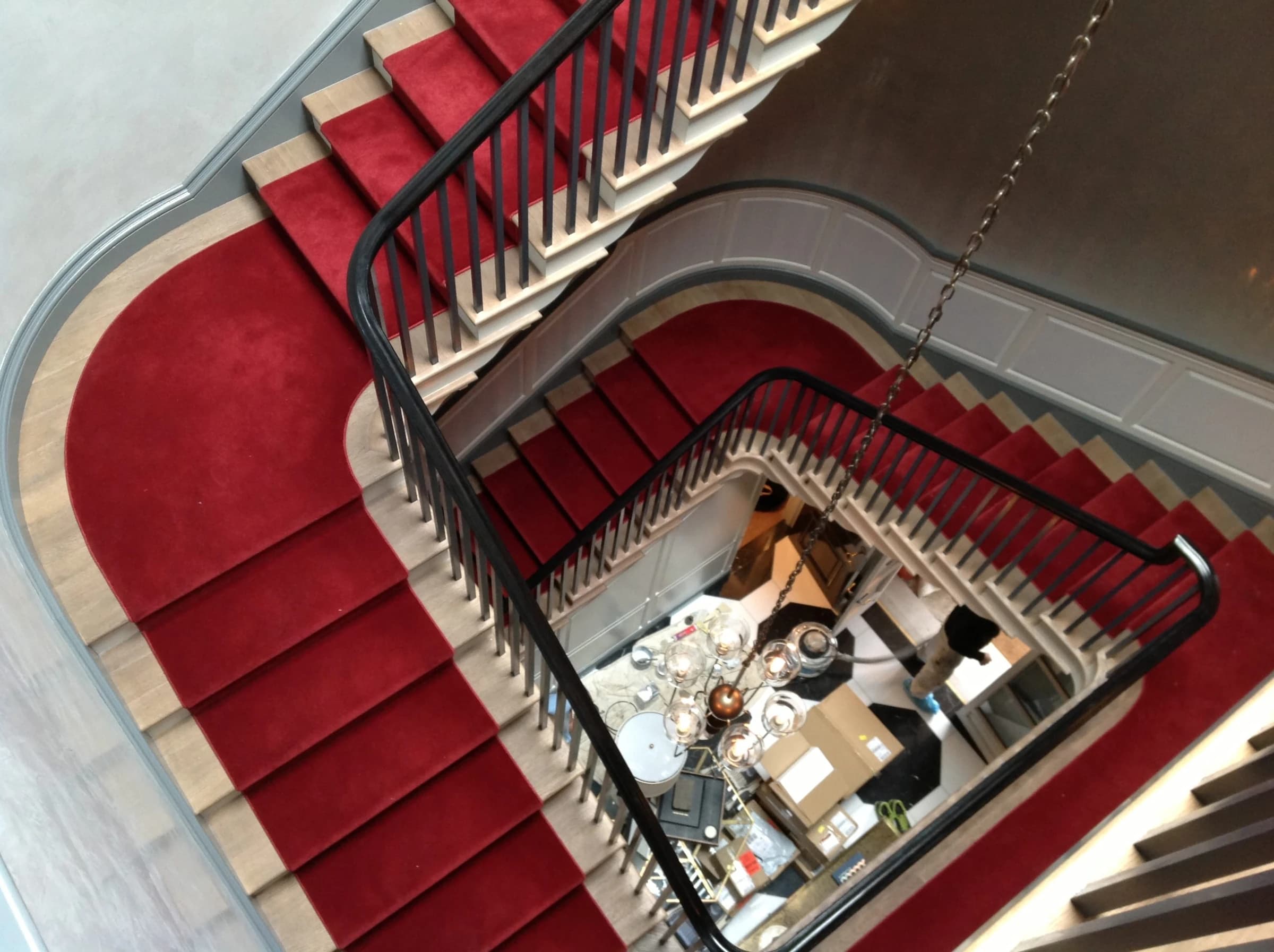 The completed curved Lincoln Park stairwell with dark handrails and a red runner.